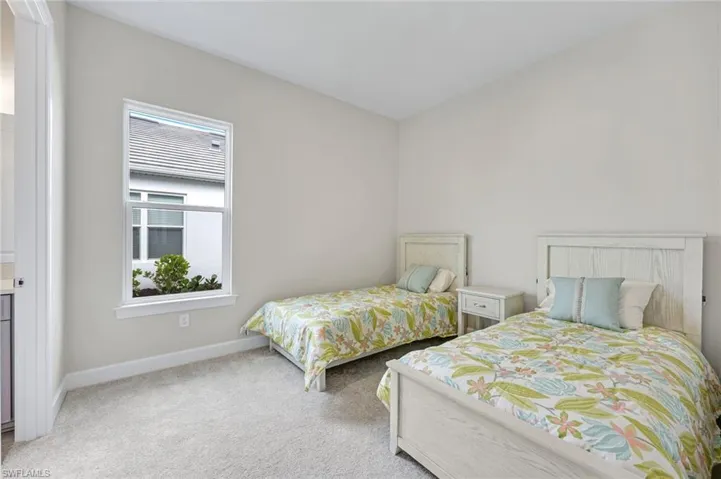 Bedroom with light colored carpet and baseboards