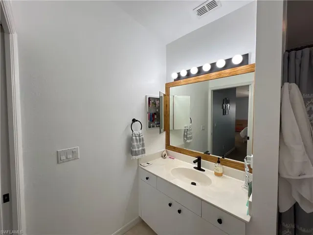 Bathroom vanity featuring a quartz-finish countertop, undermount sink, and matte black faucet