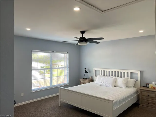 Spacious bedroom featuring light blue walls, recessed lighting, a ceiling fan with integrated light, and a large window with horizontal blinds