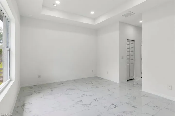 Unfurnished room with a tray ceiling and light tile flooring