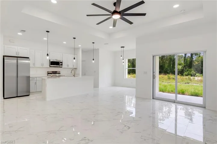 Kitchen with a raised ceiling, stainless steel appliances, white cabinetry, and light tile floors