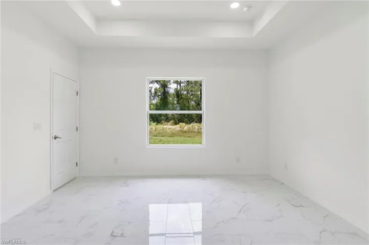 Tiled spare room featuring a tray ceiling