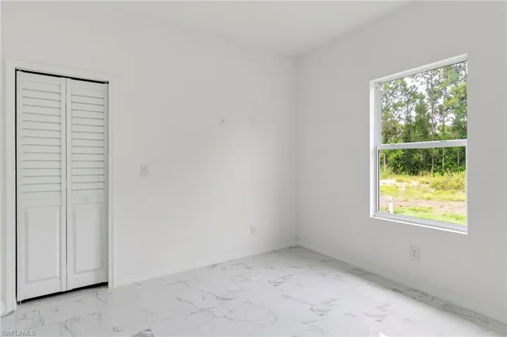 Unfurnished bedroom featuring a closet, light tile flooring, and multiple windows