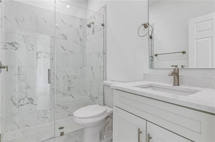 Bathroom with tile floors, walk in shower, toilet, and large vanity