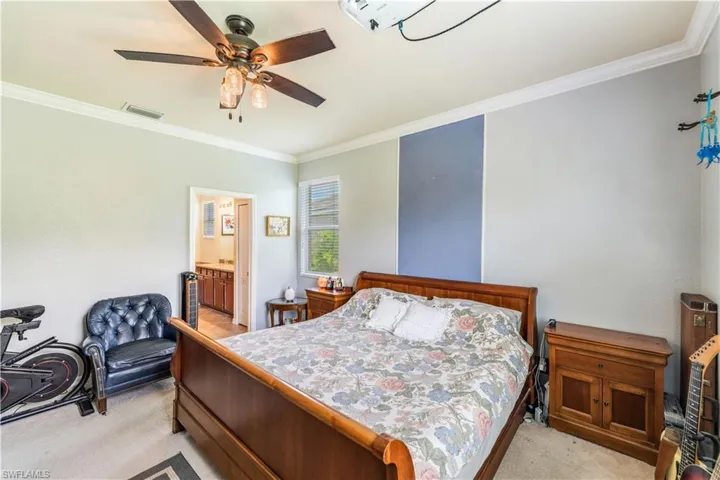 Carpeted bedroom featuring ensuite bathroom, ceiling fan, and crown molding