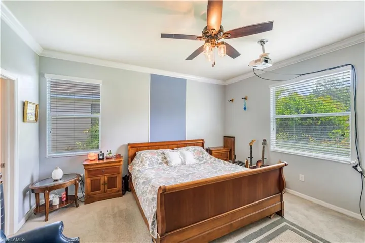 Carpeted bedroom with crown molding and ceiling fan