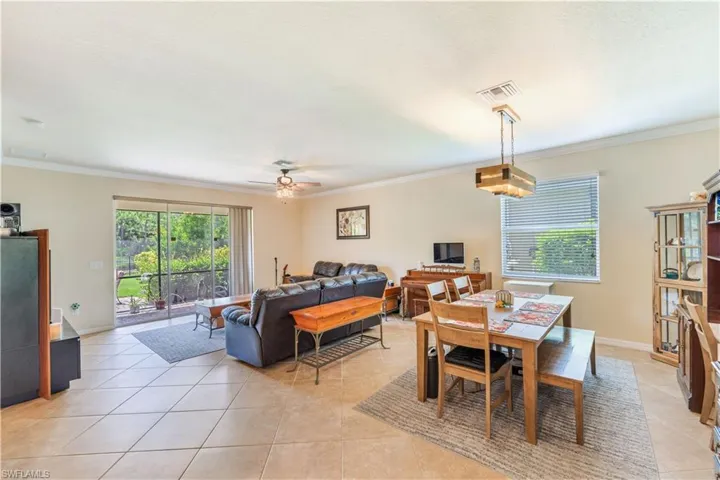 Tiled dining room featuring ceiling fan and ornamental molding