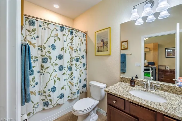 Full bathroom featuring tile patterned floors, shower / bathtub combination with curtain, toilet, and vanity