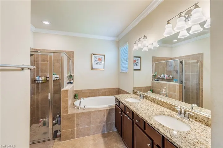 Bathroom featuring independent shower and bath, dual vanity, tile patterned flooring, and crown molding