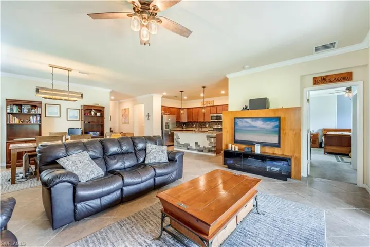 Tiled living room with ornamental molding, sink, and ceiling fan