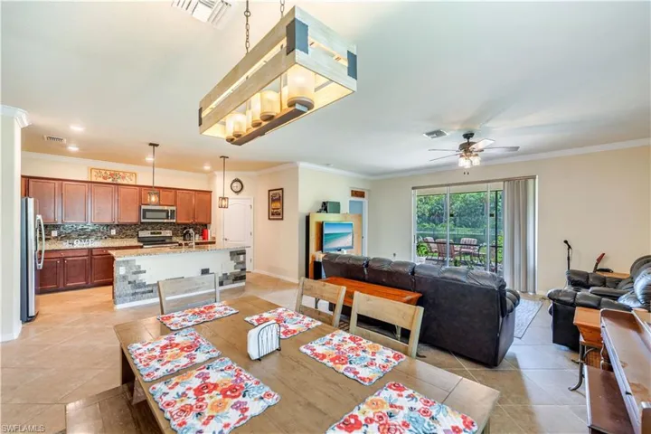 Tiled dining room featuring ceiling fan and ornamental molding