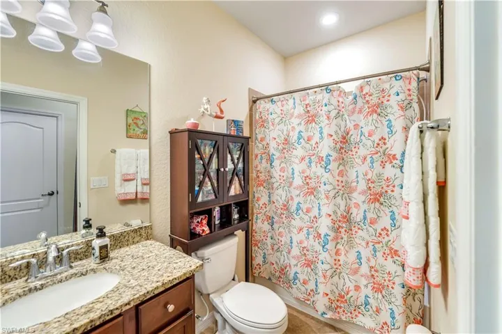 Bathroom with toilet, vanity, and an inviting chandelier