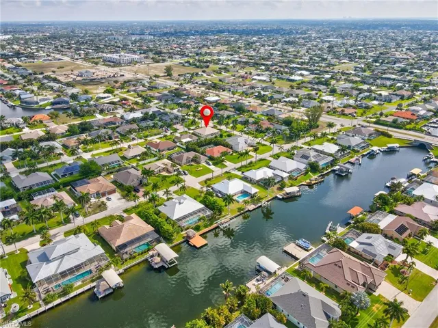 Canal-front property featuring a private boat dock, pool enclosure, and mature landscaping