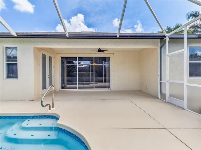 Screened-in patio with an integrated swimming pool featuring a curved entry, blue mosaic tile accents, and a stainless steel grab bar