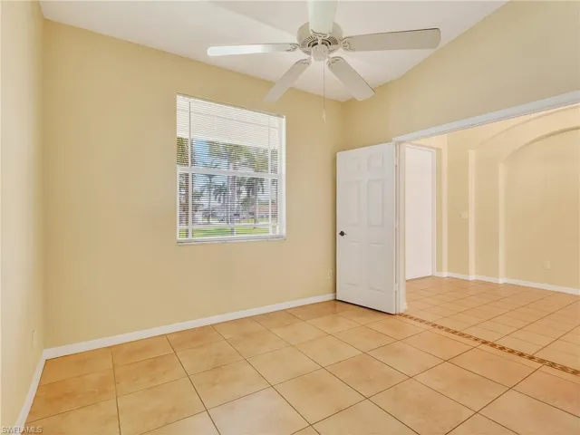 Spacious room featuring vaulted ceilings, a ceiling fan, a window with horizontal blinds, and ceramic tile flooring with a decorative tile inlay