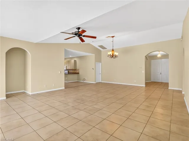 Spacious interior featuring neutral tone walls, vaulted ceiling, tile flooring