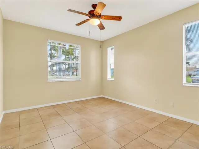 Neutral tone wall paint, ceramic tile flooring, and a ceiling fan with light fixture