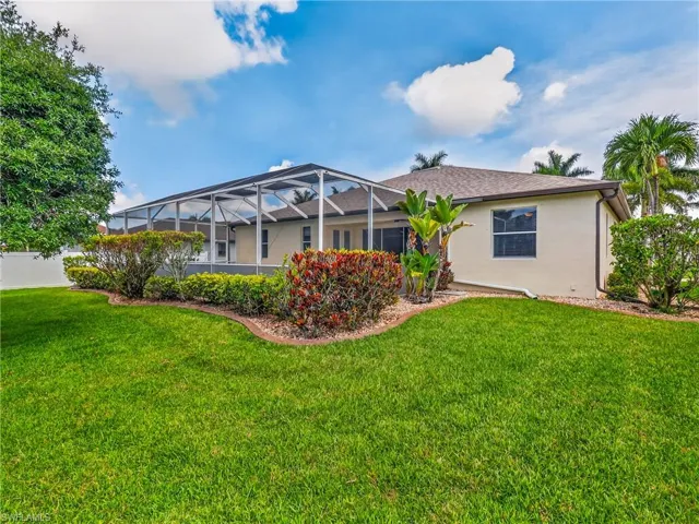 Expansive backyard featuring a lush lawn, mature landscaping, and a screened pool/patio enclosure