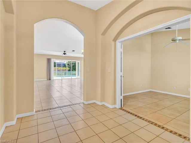 Arched doorways frame an open layout with tile flooring throughout, featuring decorative tile accents
