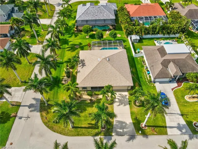 Aerial perspective featuring a property with a light-colored shingle roof, surrounded by mature royal palm trees