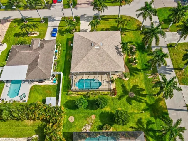 Aerial perspective showcasing a property with a screened-in pool and surrounding patio