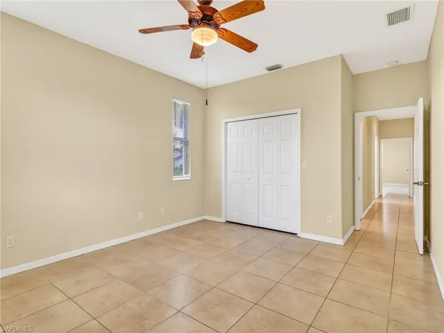 Spacious room featuring tile flooring, a ceiling fan with integrated lighting, a single window, and a bi-fold closet