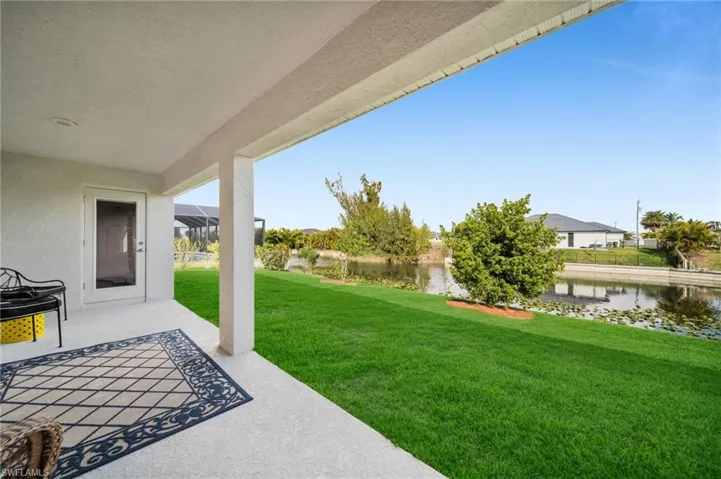 View of green lawn featuring a patio and a water view