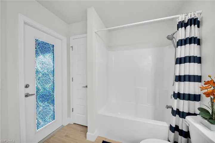 Bathroom with shower / bathtub combination with curtain and light wood-style floors