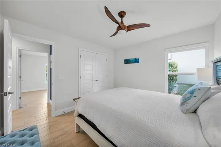 Bedroom featuring light wood-type flooring, a ceiling fan, a closet, and multiple windows