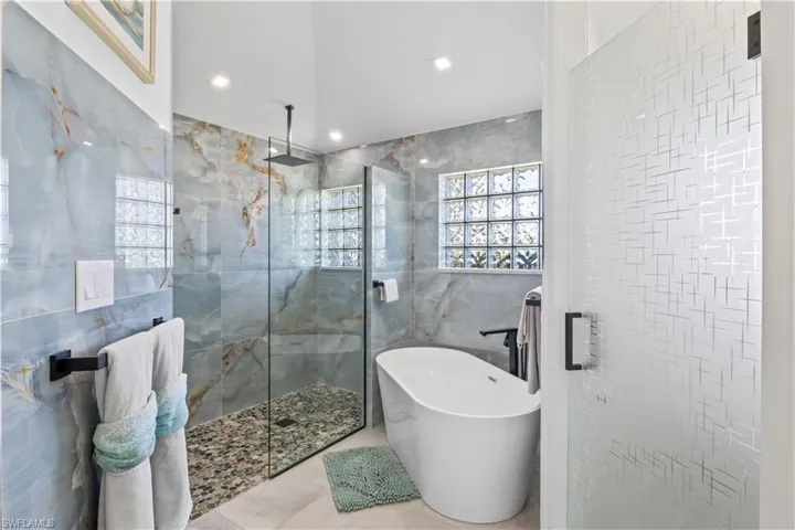 Full bath featuring a freestanding bath, tile walls, and tiled shower