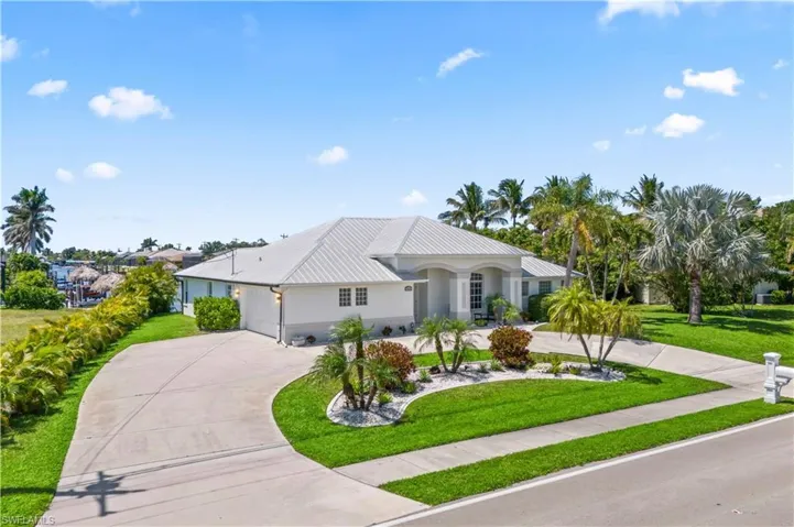 View of front facade featuring a front yard, metal roof, and curved driveway