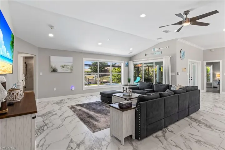 Living room featuring baseboards, a ceiling fan, recessed lighting, marble finish floor, and lofted ceiling