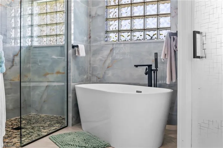 Bathroom featuring a shower stall, a freestanding tub, and tile walls