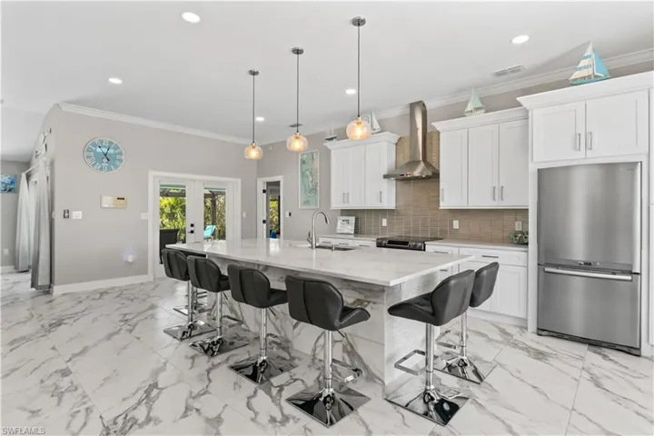 Kitchen featuring visible vents, wall chimney exhaust hood, a sink, appliances with stainless steel finishes, and decorative backsplash