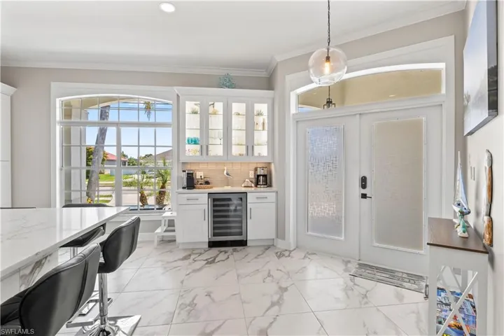 Bar with wet bar, ornamental molding, marble finish floor, beverage cooler, and decorative backsplash