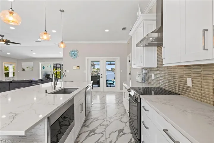 Kitchen featuring tasteful backsplash, wall chimney exhaust hood, a sink, recessed lighting, and stainless steel appliances
