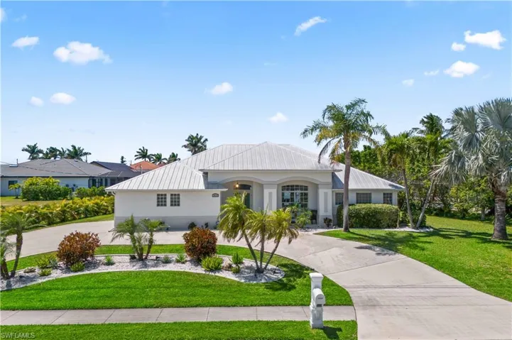 View of front facade with a garage, stucco siding, a front lawn, and curved driveway