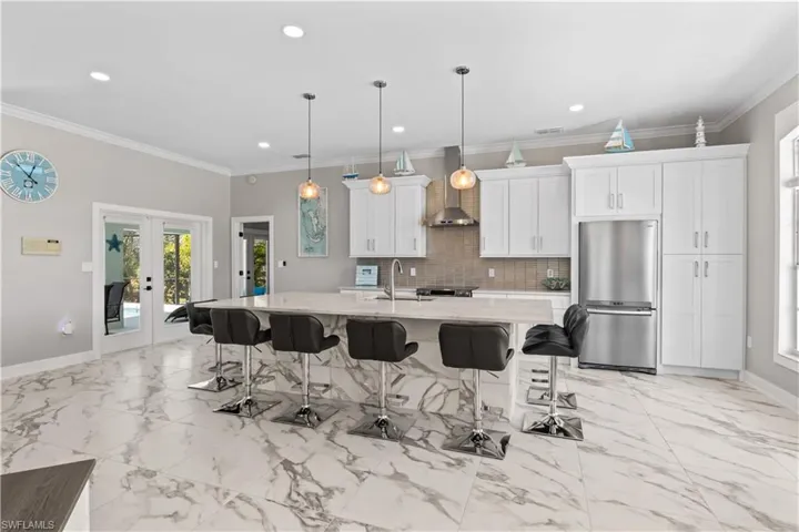 Kitchen featuring wall chimney range hood, white cabinets, appliances with stainless steel finishes, a breakfast bar area, and backsplash