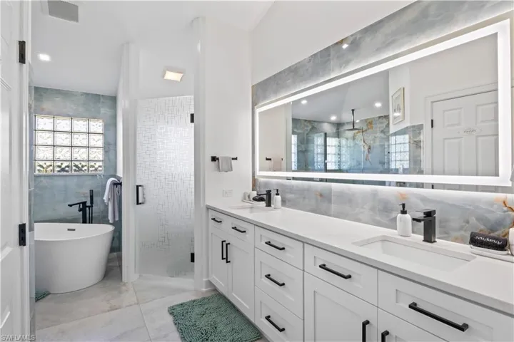 Bathroom with a shower stall, a sink, visible vents, and tile walls