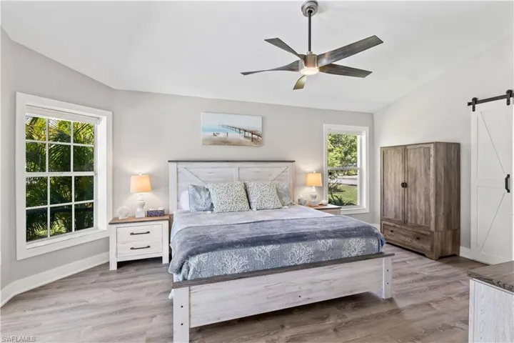 Bedroom with a barn door, multiple windows, and wood finished floors