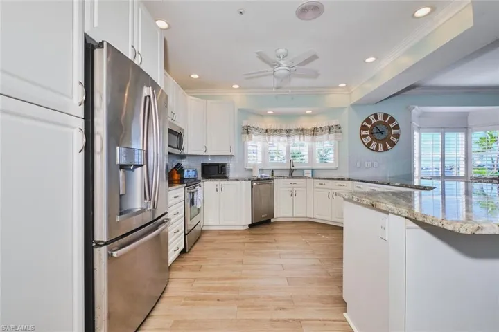 Main Kitchen featuring appliances with stainless steel finishes, white cabinets, light stone countertops, decorative backsplash, and recessed lighting