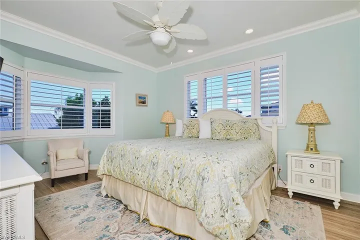 Main living area - Bedroom featuring multiple windows, crown molding, wood finished floors, a ceiling fan, and recessed lighting