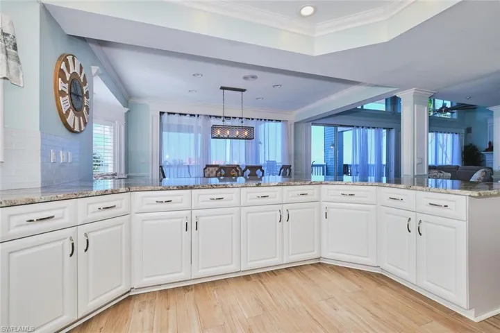 Main Kitchen with crown molding, white cabinets, light stone counters, plenty of natural light, and recessed lighting