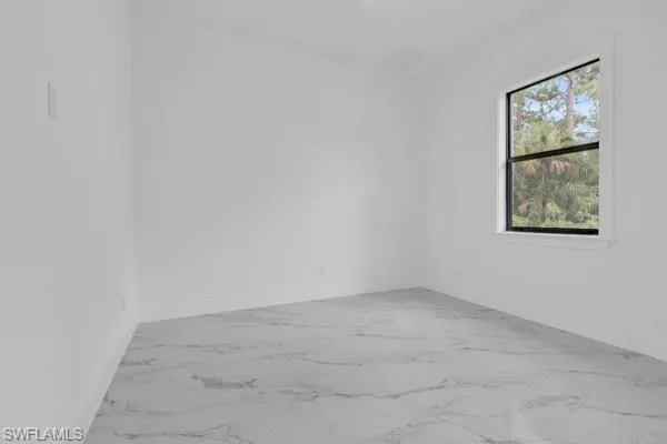 Empty room featuring light marble finish floors and baseboards