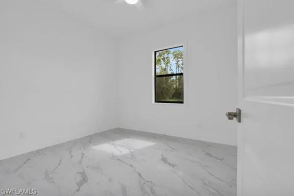 Spare room with light marble finish flooring and baseboards
