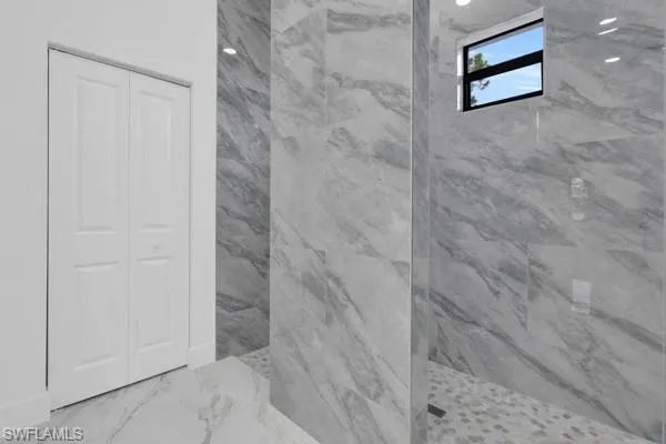 Full bathroom featuring a marble finish shower, marble finish flooring, and a closet