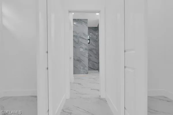 Hallway with baseboards and light marble finish flooring