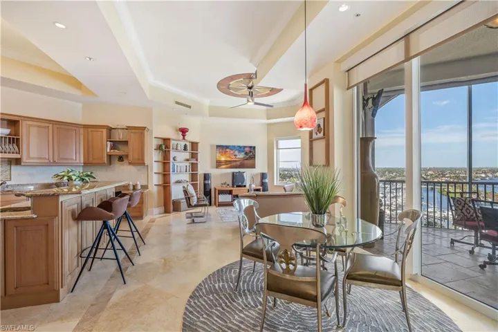 Dining space with ornamental molding, sink, ceiling fan, and a raised ceiling