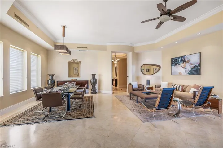 Living room featuring ceiling fan with notable chandelier and crown molding