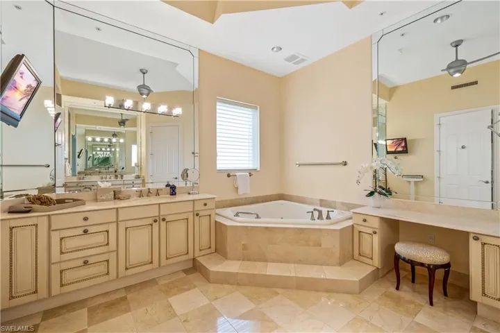 Bathroom featuring a relaxing tiled tub, vanity, and tile patterned flooring